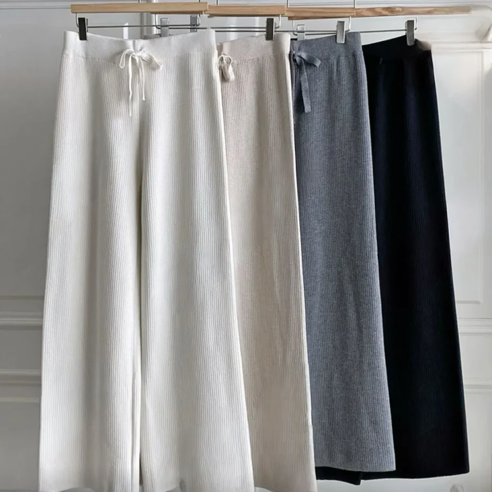 Four pairs of wide-leg knit trousers hanging in cream, grey, taupe and black