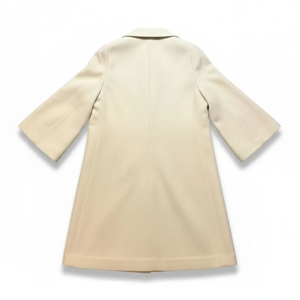 Wool-Blend Long Coat — A long, collarless wool-blend coat with a clean front and no belt. Cream, lined to the hem.